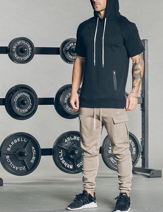 Man wearing Men's Cargo Joggers with a black hoodie in a gym setting, showcasing style and utility.